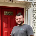 Yaroslav Marusiak, owner of All Dwelling Solutions, in front of a red front door he installed